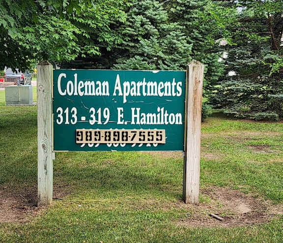 A sign for Coleman Apartments with a phone number on it.