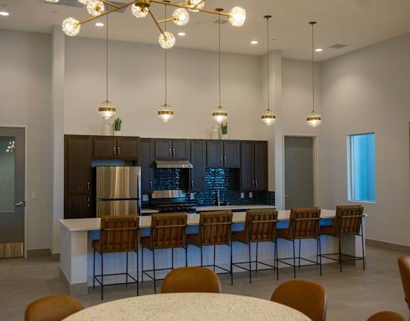 A modern kitchen with a bar area and chairs around it.