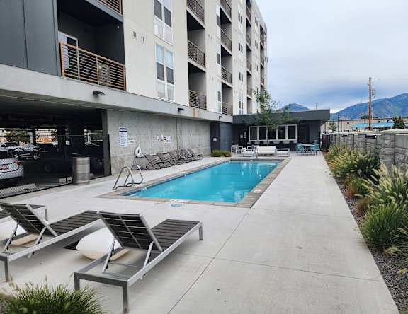 A pool area with sun loungers and a building in the background.