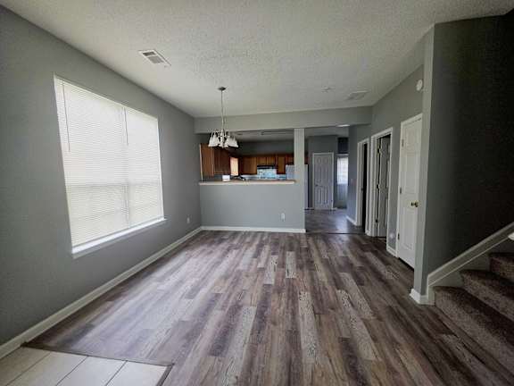A room with wooden flooring and a chandelier.