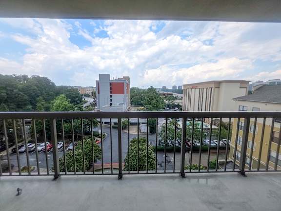 A balcony overlooks a parking lot and buildings.