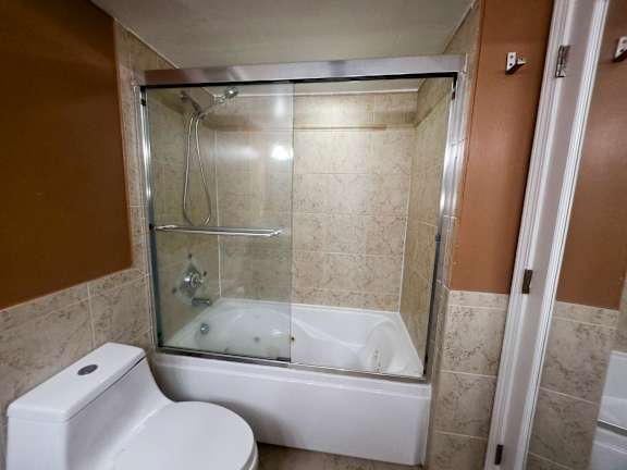 A white toilet is next to a walk-in shower.