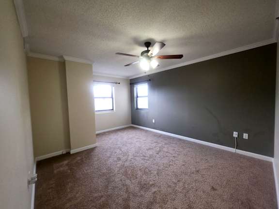 A room with a ceiling fan and carpeted floor.