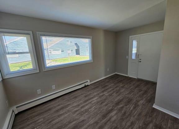 an empty living room with three windows and a door