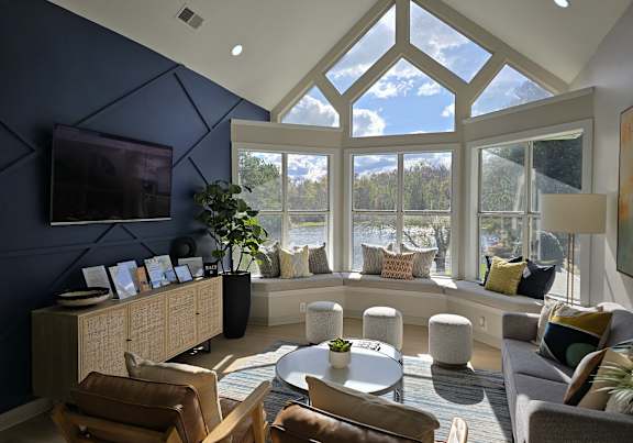 A living room with a large window and a TV on the wall.