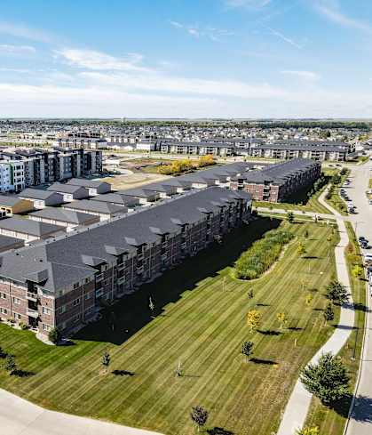 A large apartment complex with a parking lot in front.