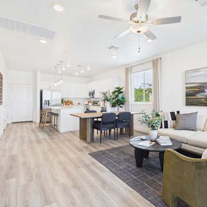 A modern living room with a dining area and kitchen in the background.