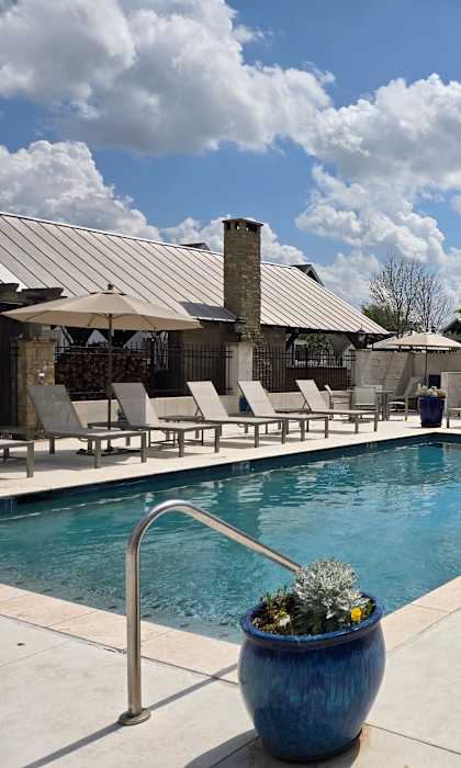 A pool area with a blue pot in the foreground and a building in the background.
