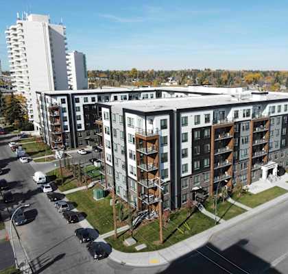 A large apartment complex with a parking lot in front.