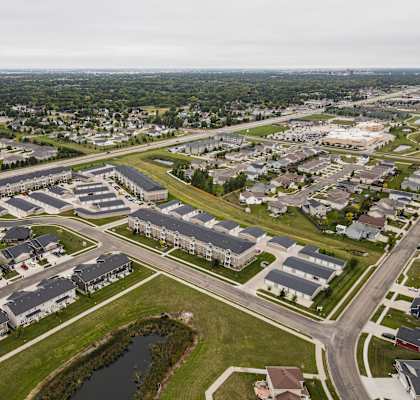 A bird's eye view of a suburban neighborhood with houses and a pond.