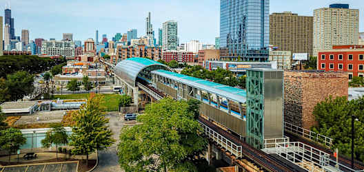 a train on the tracks in front of a city skyline at 23rd Place Apartments, Chicago, Illinois