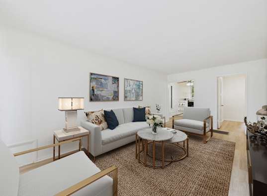 A living room with a white couch, a coffee table, and a painting on the wall.
