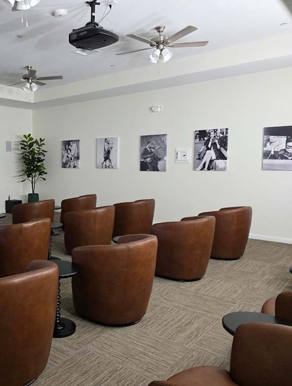A room with brown chairs and a white screen on the wall.
