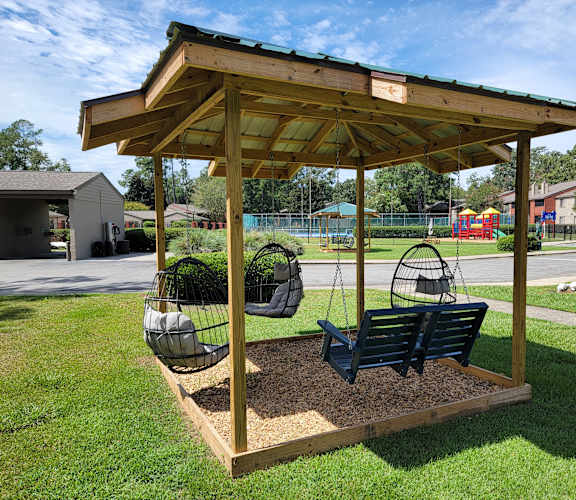 A wooden swing set with a canopy and two swings.
