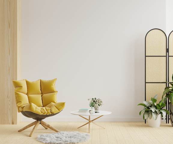 A yellow chair with a white table and potted plants in a room.