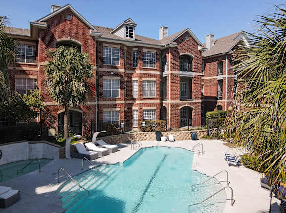 A large brick building with a pool in front.