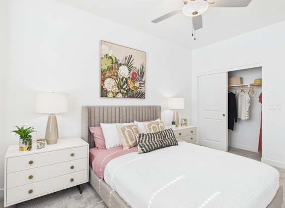 A bedroom with a large bed, a dresser, and a ceiling fan.