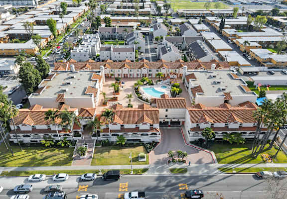 A view of a residential area with a swimming pool and cars parked on the street.