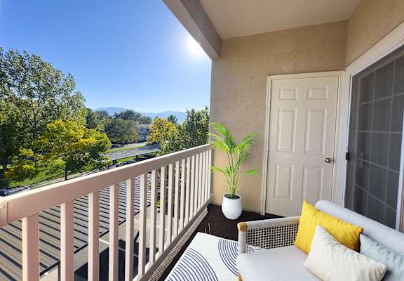 A balcony with a white couch and a potted plant.
