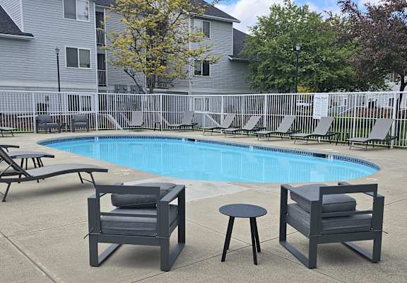 a swimming pool with chairs and tables around it