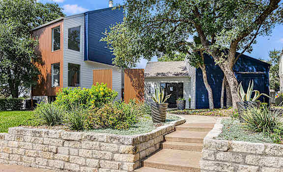 a stone retaining wall in front of a house with stairs at Peaks at Northwest Hills Apartments, Austin