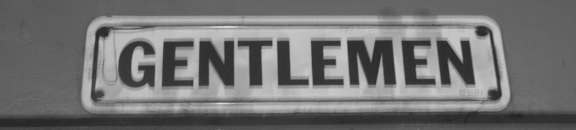 A sign that says "GENTLEMEN" is on a wall.