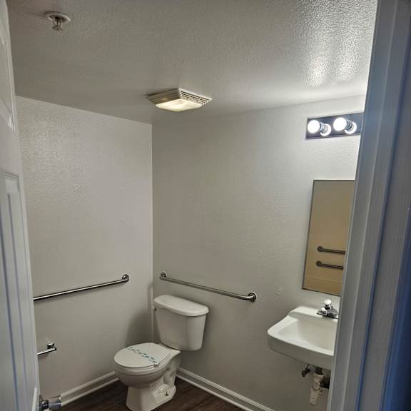 A white toilet with a white tank and a white door is in a bathroom.