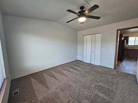 A room with a ceiling fan and carpeted floor.
