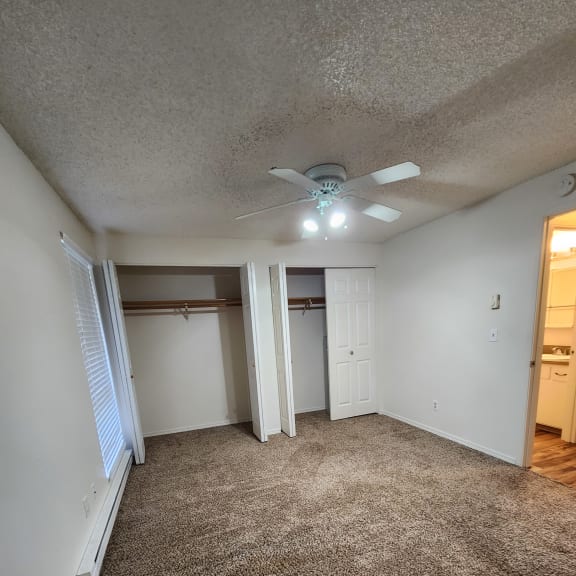 a bedroom with a large window and a ceiling fan