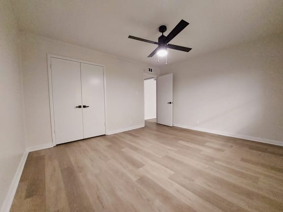 an empty living room with white walls and a ceiling fan