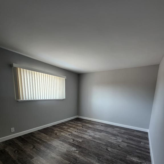a window with blinds in a room with a whitewall