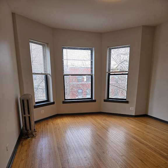 A room with a wooden wall and three windows.