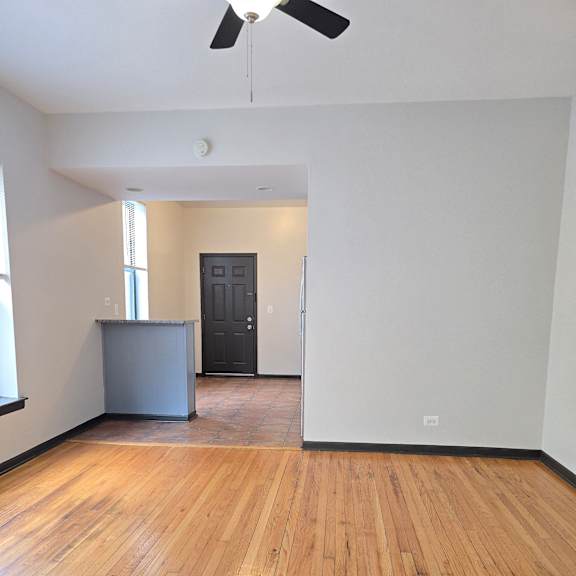 A room with a wooden wall and a black fan.