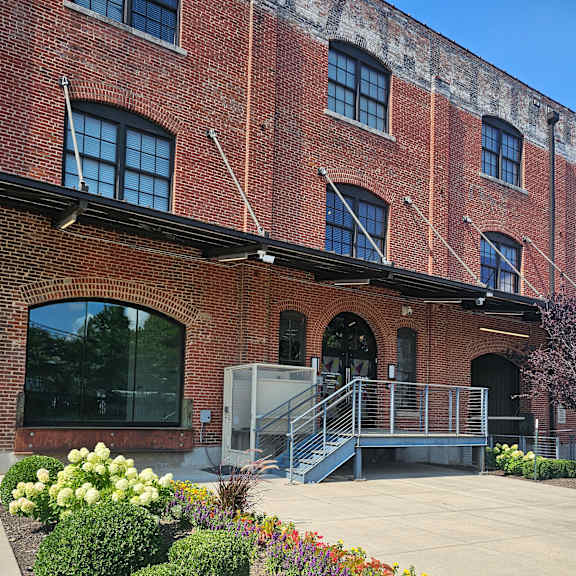 A red brick building with a flower bed in front of it.
