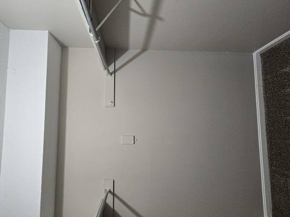 an empty room with a white wall and a staircase