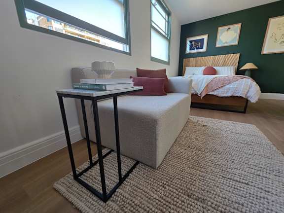 A bedroom with a bed, a nightstand, and a table with a book on it.