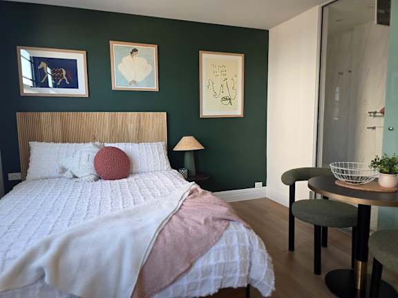 A bedroom with a bed, a chair, a table, and a lamp.