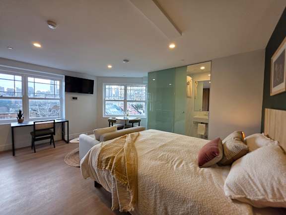 A bedroom with a large bed and a desk with a chair.