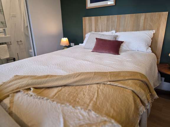A bed with a white comforter and a red pillow is in the foreground.
