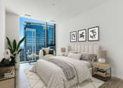 Thumbnail 4 of 21 - A bedroom with a large bed and a view of a cityscape outside the window at One 333, Chicago, Illinois