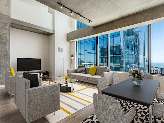 A modern living room with a grey sofa, a black coffee table, and a large window overlooking the city at One 333, Chicago, 60605