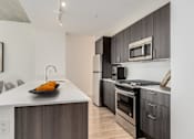 Thumbnail 5 of 21 - A modern kitchen with a white countertop and dark wood cabinets at One 333, Chicago, Illinois, 60605