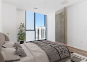 Thumbnail 11 of 21 - A bedroom with a large bed and a view of a cityscape through the window at One 333, Chicago, Illinois, 60605