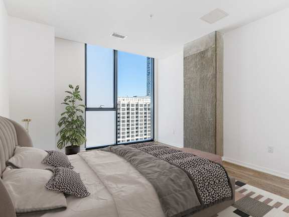 A bedroom with a large bed and a view of a cityscape through the window at One 333, Chicago, Illinois, 60605