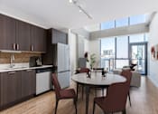 Thumbnail 12 of 21 - A modern kitchen with brown cabinets and a dining table with four chairs at One 333, IL, 60605