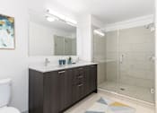 Thumbnail 20 of 21 - A bathroom with a white toilet, a sink with a mirror above it, and a walk-in shower at One 333, Chicago, 60605