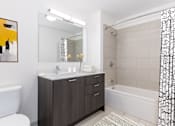 Thumbnail 17 of 21 - A bathroom with a white tub, sink, and shower curtain at One 333, Chicago