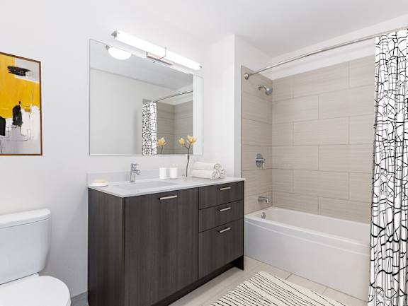 A bathroom with a white tub, sink, and shower curtain at One 333, Chicago
