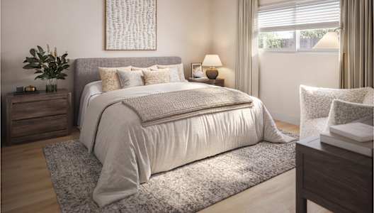 A bedroom with a large bed, a ceiling fan, and a nightstand with a plant on it.