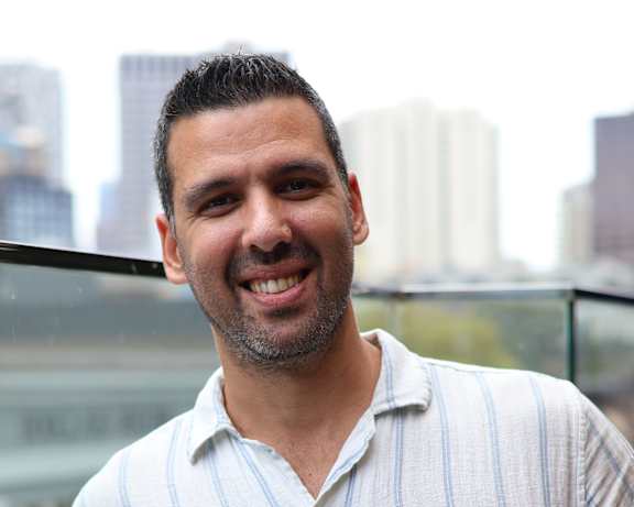 A man in a striped shirt is holding a phone to his ear.